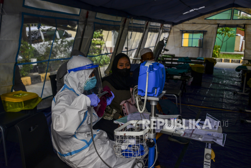 Petugas kesehatan saat memeriksa kondisi pasien positif Covid-19 yang ditampung di tenda darurat Covid-19 di RSUD Kramat Jati, Jakarta Timur, Jumat (25/6).