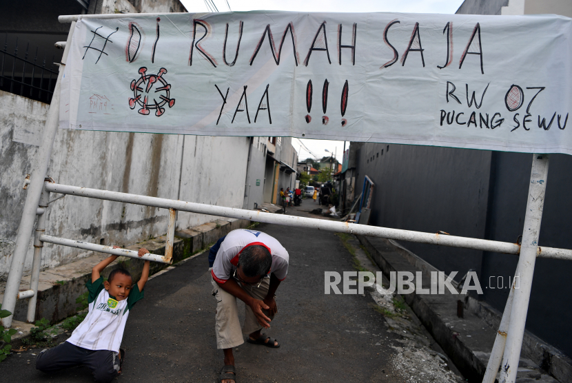 Warga melintas di depan pintu masuk Kampung Pucang Sewu yang melakukan karantina wilayah, Surabaya, Jawa Timur, Minggu (5/4/2020). Karantina wilayah tersebut dilakukan oleh warga di kampung itu guna mencegah penyebaran Virus Corona (COVID-19)