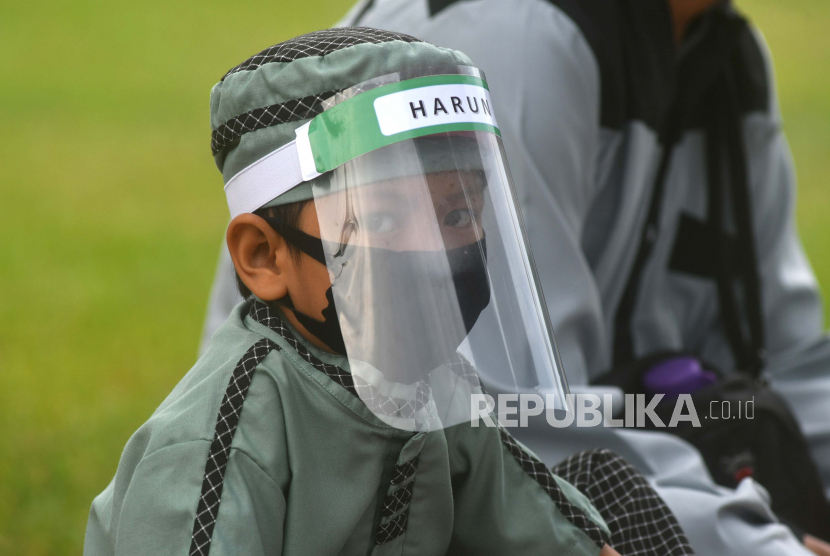 Seorang anak menggunakan alat pelindung wajah saat mengikuti shalat Idul Adha berjamaah di Lapangan Vatulemo, Palu, Sulawesi Tengah, Jumat (31/7/2020). Berbagai alat pelindung diri digunakan oleh warga saat mengikuti pelaksanaan shalat Idul Adha berjamaah guna mencegah penyebaran COVID-19.