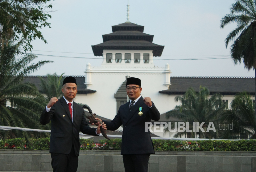Ridwan Kamil menyerahkan kujang kepada Penjabat (Pj) Gubernur Jawa Barat Bey Machmudin (kiri) saat prosesi pelepasan gubernur Jawa Barat 2018-2023 di Lapangan Gasibu, Kota Bandung, Selasa (5/9/2023). 