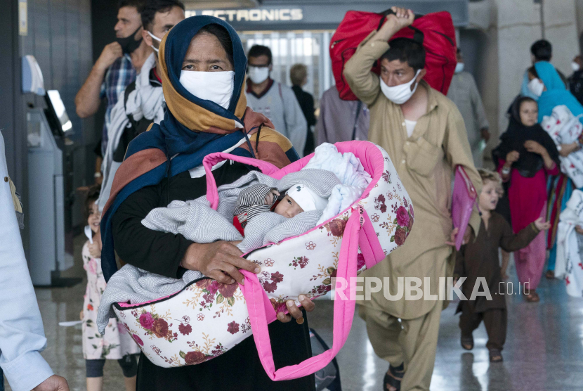 Keluarga dievakuasi dari Kabul, Afghanistan, berjalan melalui terminal sebelum naik bus setelah mereka tiba di Bandara Internasional Washington Dulles, di Chantilly, Va, pada Kamis, 26 Agustus 2021.