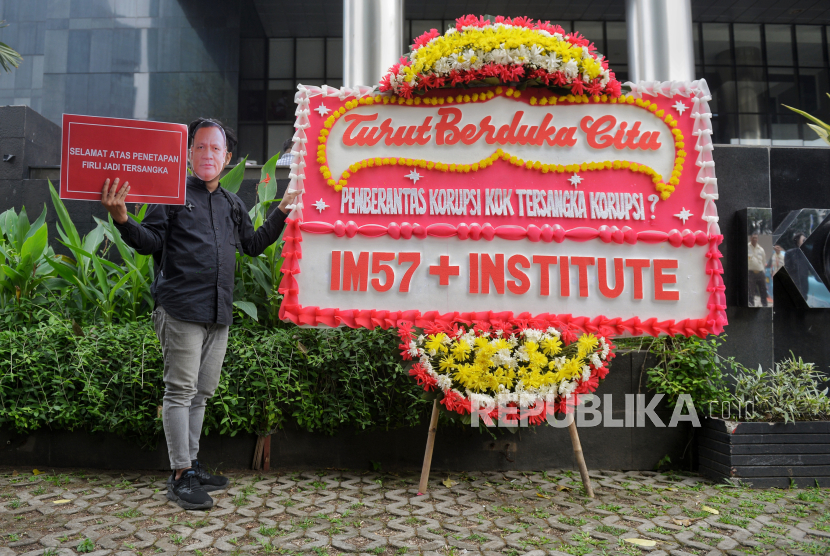 Koalisi Masysrakat Sipil Anti Korupsi berfoto di karangan bunga saat nenggelar aksi di depan Gedung Merah Putih KPK, Jakarta Selatan, Kamis (23/11/2023). 
