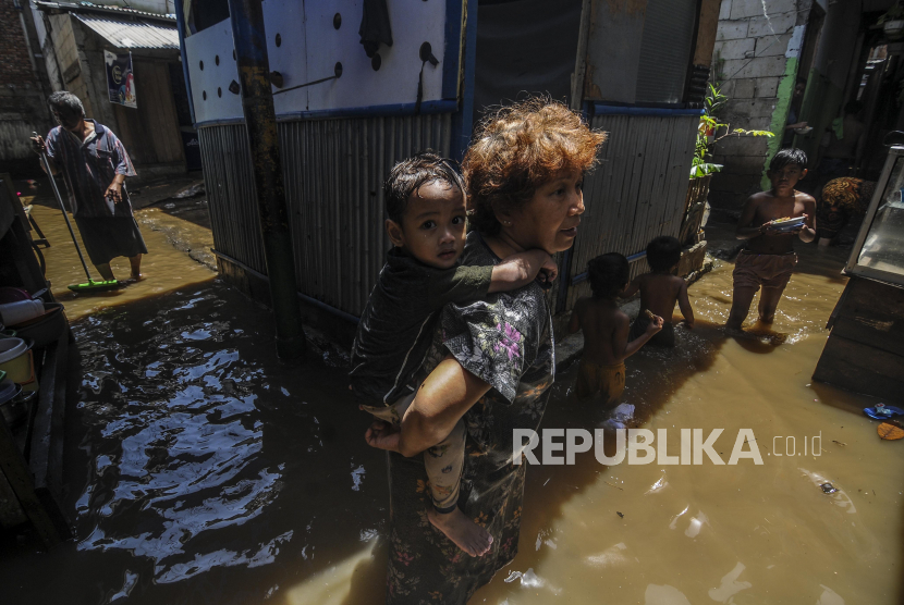 Warga menggendong anaknya saat terjadi banjir di kawasan Kebon Pala, Jakarta, Senin (5/10). Hujan deras di wilayah Jabodetabek pada Ahad (4/10) malam, membuat sebanyak 92 RT terendam banjir dengan rata-rata ketinggian mencapai 10-150 sentimeter. Republika/Putra M. Akbar