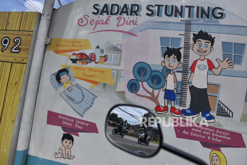 Refleksi pengendara motor melintas di dekat mural stunting di Jakarta. (ilustrasi)