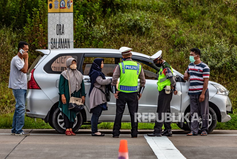 Polisi menginterogasi sejumlah penumpang yang diduga menumpang mobil bernomor polisi palsu saat penyekatan pemudik di Gerbang Tol Kalikangkung, Semarang, Jawa Tengah (26/5/2020). Satlantas Polrestabes Semarang mencatat sejak pukul 07:00 - 17:00 WIB sebanyak 276 kendaraan bermotor roda empat maupun bus yang mengangkut pemudik menuju DKI Jakarta melalui gerbang tol tersebut diperintahkan untuk memutar balik karena tidak dilengkapi surat ijin keluar-masuk (SIKM)