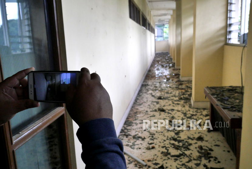 Jurnalis mengambil foto kondisi sekolah yang rusak dilempar batu. (Ilustrasi)