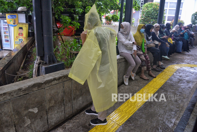 Warga mengenakan jas hujan untuk beraktivitas di Stasiun Tebet, Jakarta