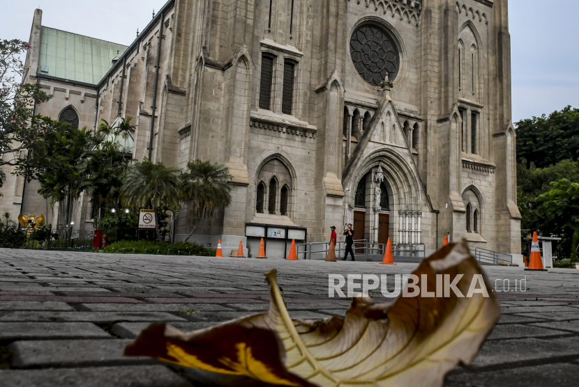 Warga melintas di depan pintu Gereja Katedral, Jakarta, Ahad (5/4). Sekretaris Umum Persatuan Gereja Indonesia (PGI) Pendeta Jacky Manuputty mengusulkan penggunaan gereja kosong untuk isolasi atau karantina bagi pasien terjangkit virus corona jenis baru (Covid-19). 