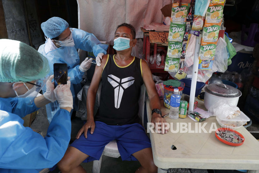  Dokter Kenneth Maturgo mengambil foto saat petugas kesehatan menyuntik Leopoldo Lacadan dengan vaksin COVID-19 Sinovac China di samping toko sementara di Manila, Filipina pada hari Rabu, 19 Mei 2021. 