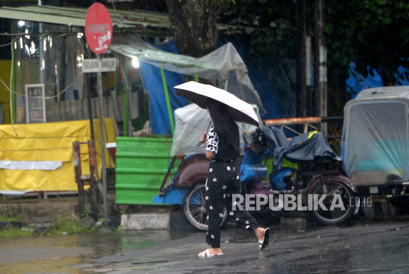 Wisatawan menggunkan payung saat hujan di kawasan Ngabean, Yogyakarta, Rabu (28/12/2022). Badan Meteorologi Klimatologi dan Geofisika (BMKG) Daerah Istimewa Yogyakarta (DIY) memperkirakan bahwa Jogja dilanda cuaca ekstrem pada 28 hingga 30 Desember 2022. Kondisi tersebut membuat potensi curah hujan dengan intensitas sedang hingga lebat serta petir dan angin kencang.