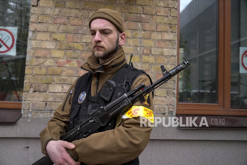 Seorang pria pertahanan sipil bersenjata memegang senapan serbu Kalashnikov saat berpatroli di jalan kosong karena jam malam di Kyiv, Ukraina, Ahad, 27 Februari 2022. 