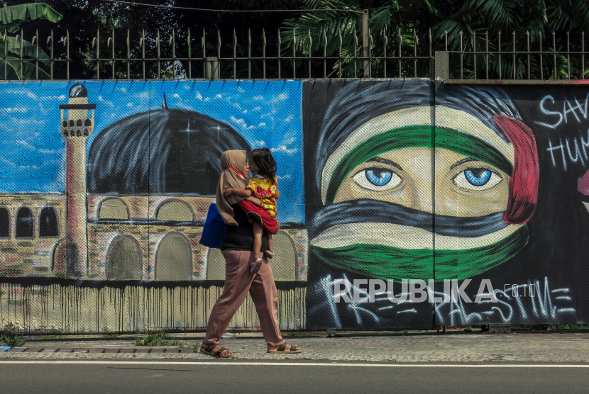 Palestina: Warga melintas di depan mural solidaritas untuk Palestina di Jalan Raya Jakarta-Bogor, Depok, Jawa Barat, Jumat (21/5/2021). Mural tersebut ditujukan sebagai bentuk solidaritas dan dukungan kepada warga Palestina atas serangan pasukan Israel. 