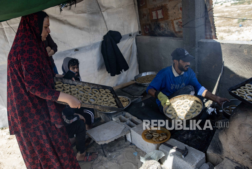 Seorang pria Palestina membuat kue tradisional sebelum Idul Fitri, yang menandai akhir bulan suci Ramadhan, di dalam tenda di kamp Rafah di selatan Jalur Gaza, 9 April 2024. 