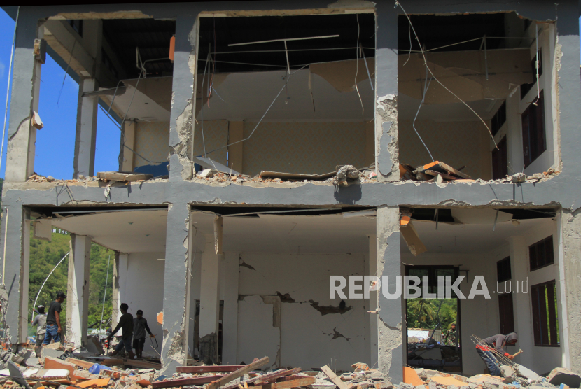 Sejumlah pekerja mencari sisa puing bangunan sekolah SMK 1 Rangas yang roboh pasca gempa bumi di Mamuju, Sulawesi Barat, Selasa (26/1/2021). 
