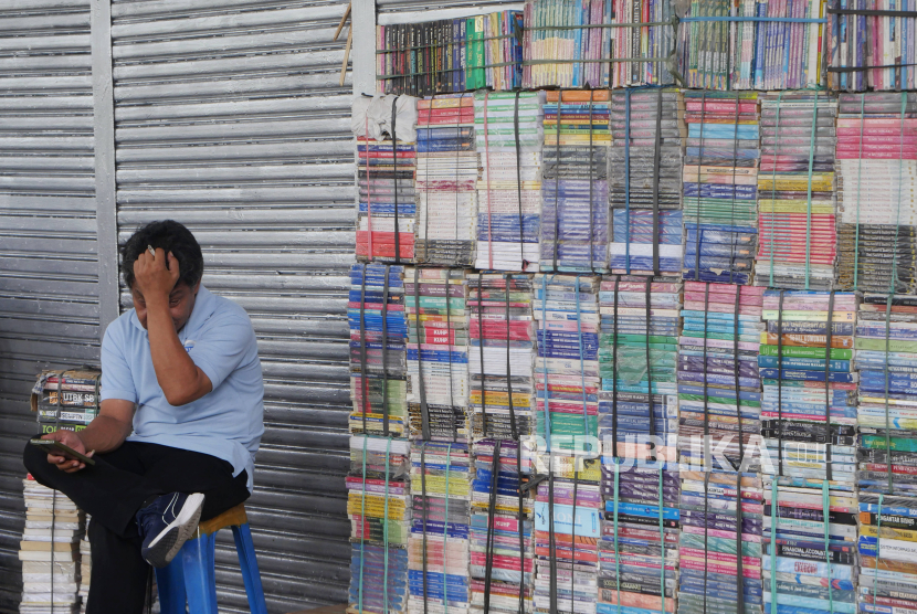 Pedagang buku duduk menunggu pembeli di Kawasan Kwitang, Senen, Jakarta, Kamis (13/6/2024). Kwitang menjadi salah sentra penjualan buku-buku di Jakarta yang sudah ada sejak tahun 1980an. Area lapak-lapak buku Kwitang itu kemudian makin dikenal ketika masuk ke dalam film fenomenal Ada Apa Dengan Cinta (AADC). Saat ini lapak para pedagang buku terbilang sepi pembeli dibanding masa jayanya. Menurut pedagang, kini  masyarakat banyak beralih membeli buku digital dan melakukan transkasi pembelian buku fisik secara daring. Biasanya pada Juli-Agustus, sentra buku kwitang ini agak ramai pengunjung karena bertepatan dengan tahun ajaran baru. Berbagai jenis buku dijual di sini mulai dari buku pelajaran sekolah, kamus, novel, komik, buku biografi, hingga sastra klasik degan harga yang terjangkau.