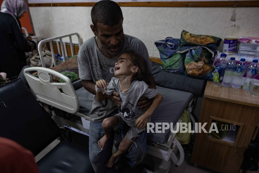 Anak Gaza yang kekurangan gizi duduk di pangkuan ayahnya di Rumah Sakit Martir Al-Aqsa di Deir Balah, Jalur Gaza, 1 Juni 2024. Selain belasan ribu syahid, puluhan ribu anak Gaza terancam kelaparan.