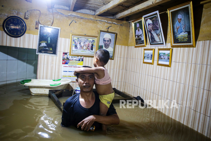 Warga menggendong anak saat berada di rumahnya saat banjir di Kebon Pala, Kampung Melayu, Jaktim. (ilustrasi)
