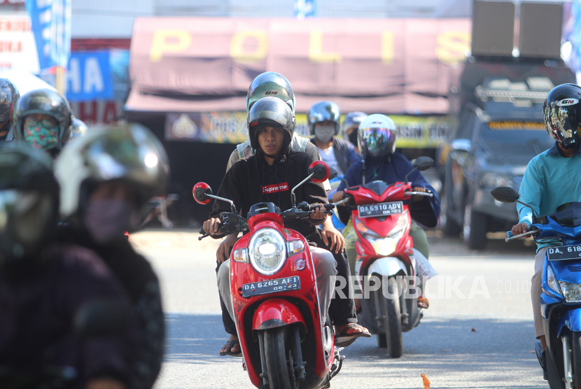 Seorang pengendara motor melintas pos Pembatasan Sosial Bersakala Besar (PSBB) tanpa menggunakan masker di jalan Ahmad Yani Banjarmasin, Kalimantan Selatan, Ahad (10/5/2020). Meskipun Kota Banjarmasin telah melanjutkan Pembatasan Sosial Berskala Besar (PSBB) tahap kedua masih banyak warga yang mengabaikan aturan berkendara seperti tidak menggunakan masker