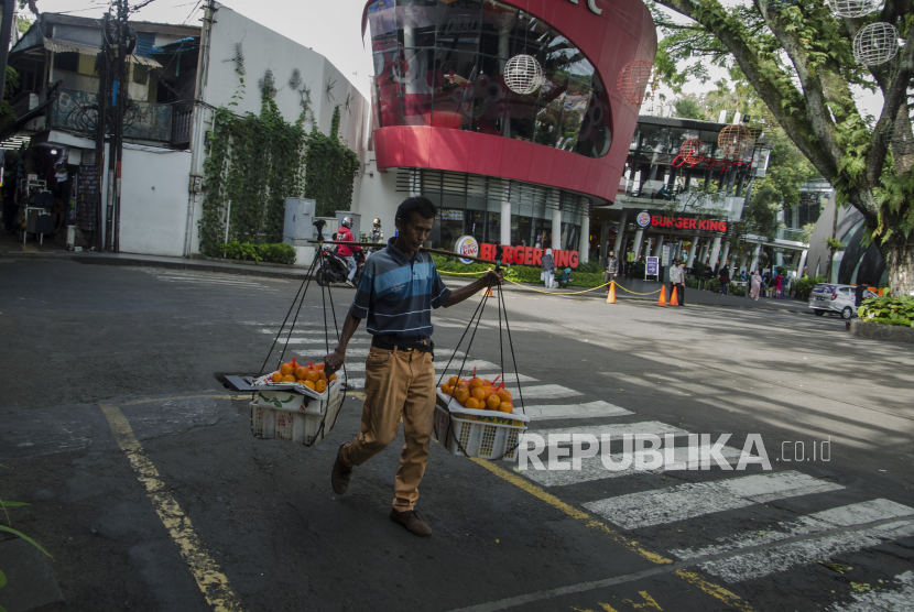 Seorang pedagang buah memikul dagangannya saat berjalan di depan Ciwalk Plaza, Bandung, Jawa Barat, Jumat (4/3/2022). Sementara angka kasus konfirmasi positif COVID-19 pada Sabtu (5/3/2022) bertambah sebanyak 30.156 orang. 