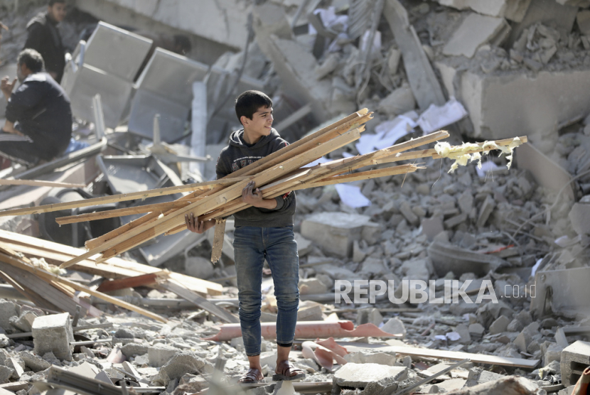 Warga Palestina mengumpulkan kayu dari kehancuran akibat serangan udara dan darat Israel di Jalur Gaza di Kota Gaza, Sabtu, (10/2/2024).
