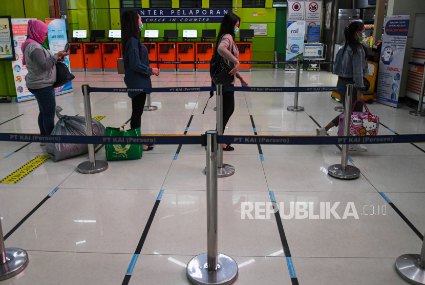 Calon penumpang antre pada pembatas stiker panduan tanda pengatur jarak sosial setiap individu (social distancing) yang dipasang dipintu keberangkatan Stasiun Gambir, Jakarta, Ahad (22/3/2020). 