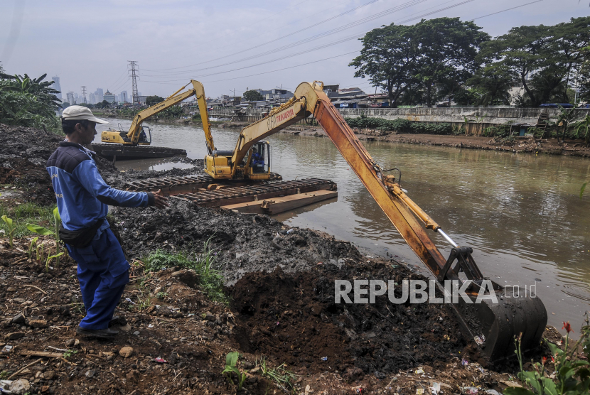 Petugas Dinas Sumber Daya Air menggunakan alat berat untuk mengeruk sampah bercampur lumpur di aliran Banjir Kanal Barat di Dukuh Atas, Jakarta Pusat.