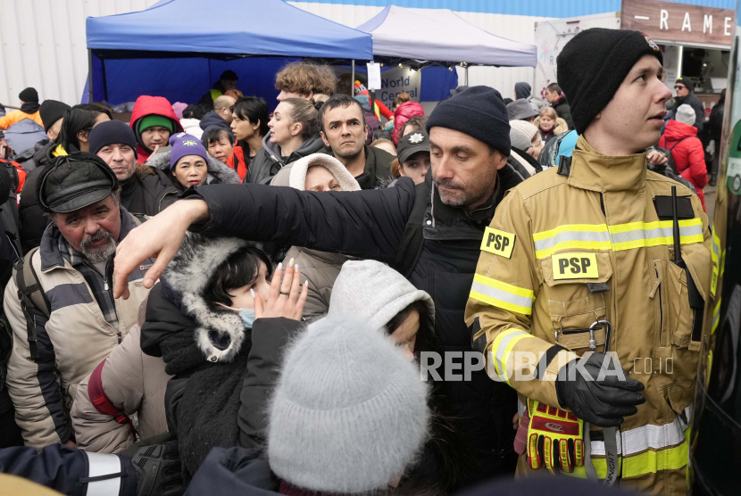 Pengungsi yang melarikan diri dari Ukraina dari kerumunan perang untuk naik bus meninggalkan perbatasan Korczowa, Polandia, Ahad, 6 Maret 2022.