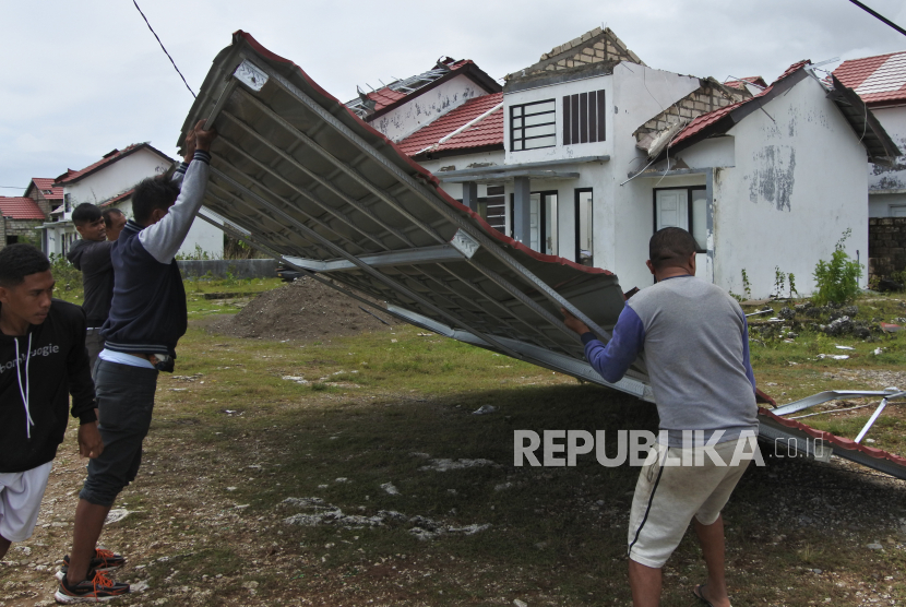 Warga bergotong royong menarik atap rumah yang jatuh di badan jalan akibat diterjang angin kencang. 