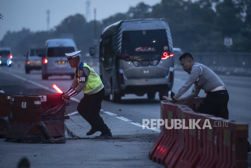 Polisi mendorong pembatas jalan menjelang pemberlakuan contraflow di kawasan Gerbang Tol Cikampek Utama, Karawang, Jawa Barat, Jumat (5/4/2024). 