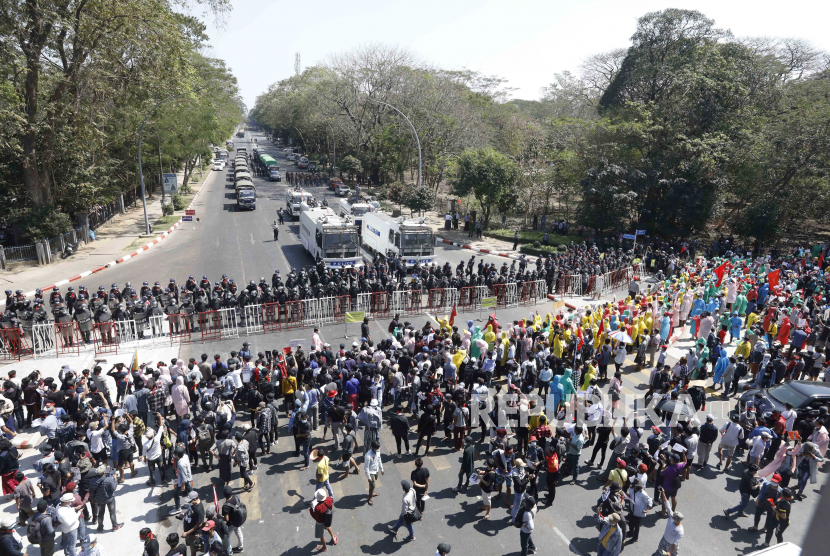  Para pengunjuk rasa meneriakkan slogan-slogan di depan petugas polisi anti huru-hara selama protes menentang kudeta militer, di Yangon, Myanmar, Selasa (9/2). Ribuan orang terus melakukan unjuk rasa di Yangon meskipun ada peringatan keras dari militer setelah beberapa hari protes massal.