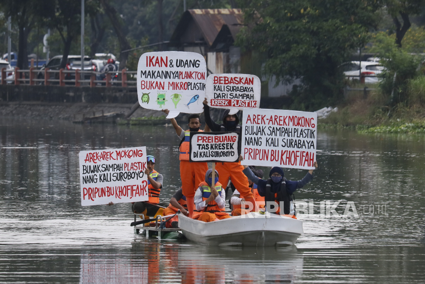 Sejumlah aktivis lingkungan membentangkan poster di atas perahu di Sungai Surabaya, Jawa Timur.