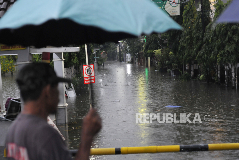 Seorang warga melihat jalan yang banjir di Jatibening, Bekasi, Jawa Barat.