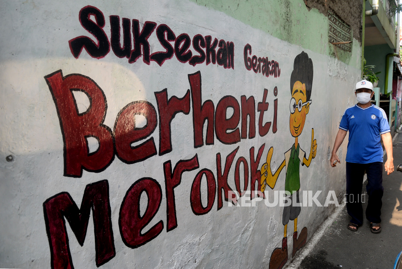 Warga melintas didekat mural bertema kawasan bebas asap rokok di lingkungan RW 06 Kelurahan Kayu Manis, Matraman, Jakarta.