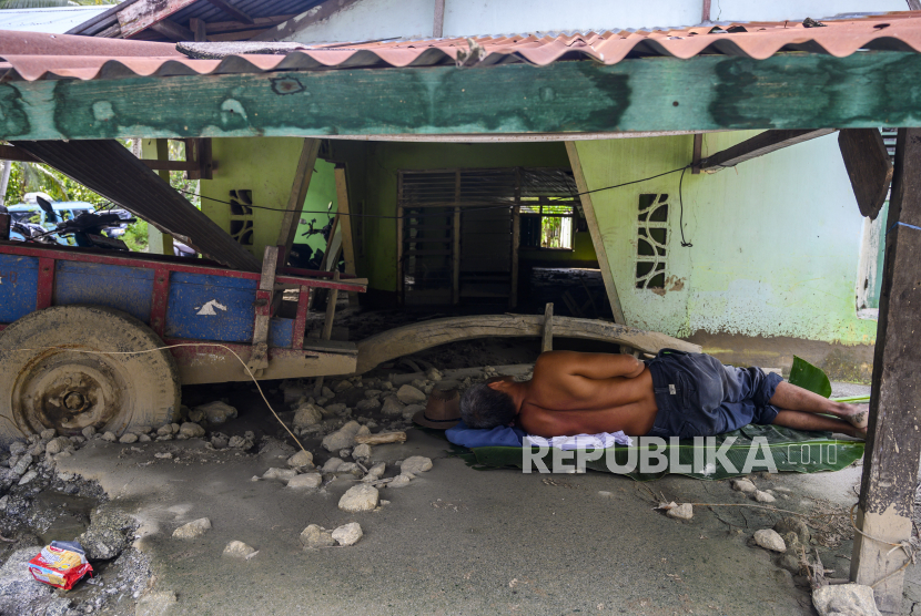 Warga tertidur di dekat rumahnya yang tertimbun lumpur akibat terjangan banjir bandang di Desa Poi, Kecamatan Dolo Selatan, Kabupaten Sigi, Sulawesi Tengah, Sabtu (16/5/2020). Banjir bandang yang menerjang desa itu pada Jumat (15/5/2020) malam mengakibatkan puluhan rumah rusak berat dan hilang diterjang banjir yang disertai dengan material batu dan lumpur