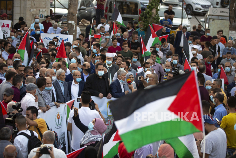 Palestina mengibarkan bendera nasional selama protes terhadap normalisasi hubungan antara Uni Emirat Arab dan Bahrain dengan Israel, di kota Ramallah Tepi Barat, Selasa, 15 September 2020. Israel akan menandatangani perjanjian dengan UEA dan Bahrain di Gedung Putih pada hari Selasa.