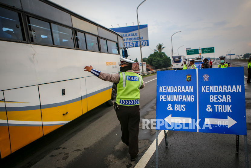Petugas kepolisian mengarahkan kendaraan umum ke pintu keluar Tol Bitung, Kabupaten Tangerang, Banten, Jumat (24/4/2020). Penyekatan itu dilakukan menyusul adanya larangan mudik bagi seluruh kalangan yang sudah ditetapkan mulai hari ini guna mencegah penyebaran COVID-19