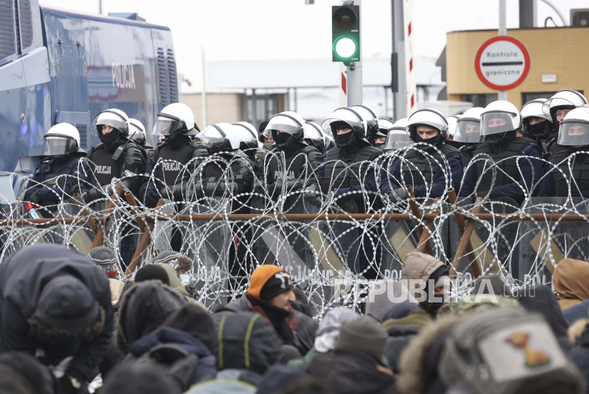 Muslim Polandia Beri Sup Hangat untuk Tentara di Perbatasan. Para migran berkumpul di depan pagar kawat berduri dan tentara Polandia di pos pemeriksaan Kuznitsa di perbatasan Belarus-Polandia dekat Grodno, Belarus, pada Senin, 15 November 2021.