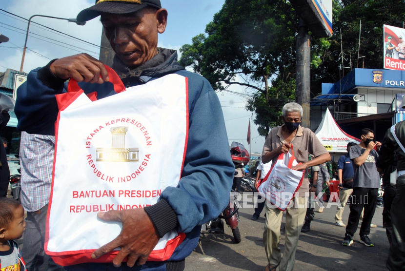 Warga menerima bantuan sembako dari Presiden Joko Widodo di Terminal Baranangsiang, Kota Bogor, Jawa Barat, Kamis (9/4/2020). Sebanyak  500 paket sembako dibagikan untuk warga yang terkena dampak ekonomi akibat wabah pandemi virus Corona (COVID-19) di Kota Bogor