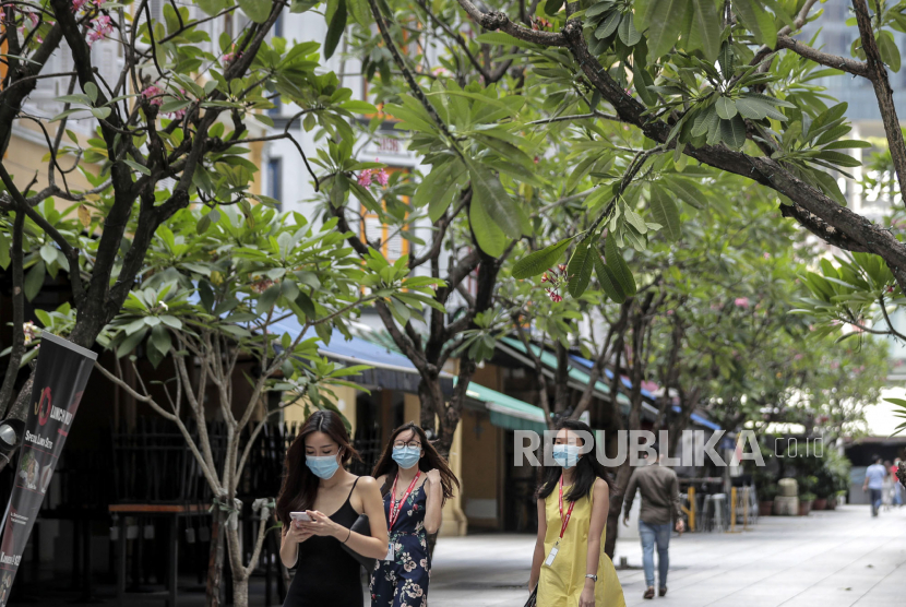 Orang-orang memakai masker bedah saat istirahat makan siang mereka di Singapura, Selasa (14/4). Singapura pada 14 April mewajibkan semua orang untuk mengenakan maker di luar rumah