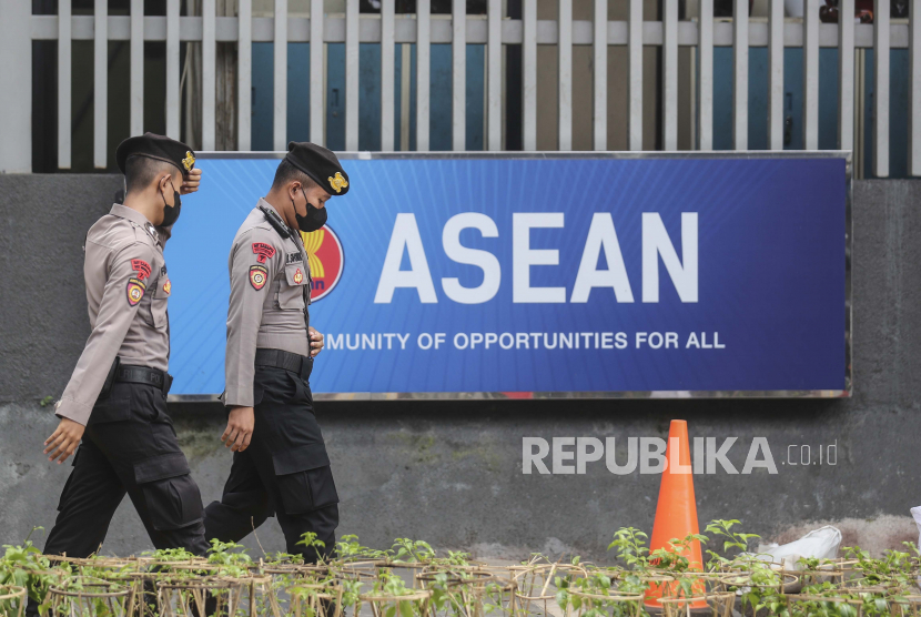Polisi berjalan melewati logo Perhimpunan Bangsa-Bangsa Asia Tenggara (ASEAN) di luar sekretariat ASEAN saat kendaraan para delegasi memasuki kompleks menjelang pertemuan khusus para menteri luar negeri ASEAN di Jakarta 27 Oktober 2022. Pertemuan khusus para menteri luar negeri ASEAN diadakan untuk membahas krisis yang sedang berlangsung di Myanmar.