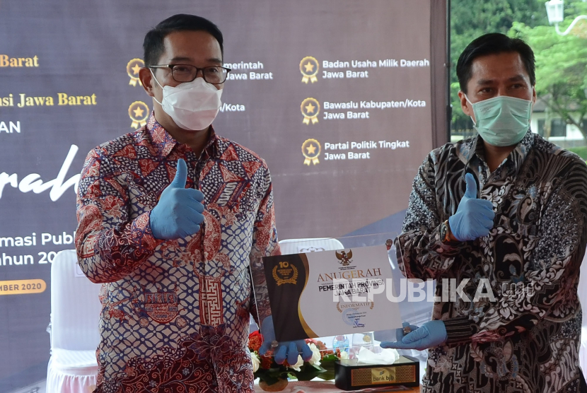Komisioner Komisi Informasi (KI) Pusat Cecep Suryadi (kanan) menyerahkan penghargaan anugerah keterbukaan informasi publik kepada Gubernur Jawa Barat Ridwan Kamil (Emil).
