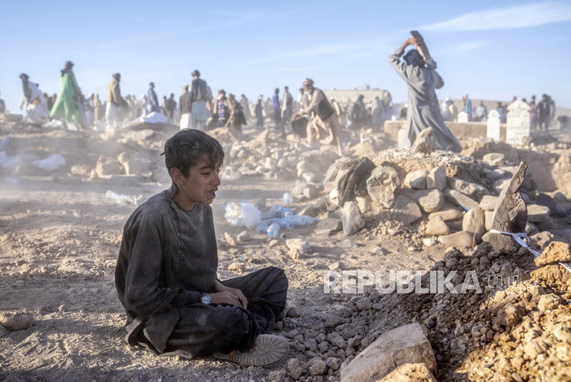 An Afghan boy grieves next to the grave of his younger brother who died in the earthquake, in Zenda Jan District of Herat Province, western Afghanistan, Monday (9/10/2023).
