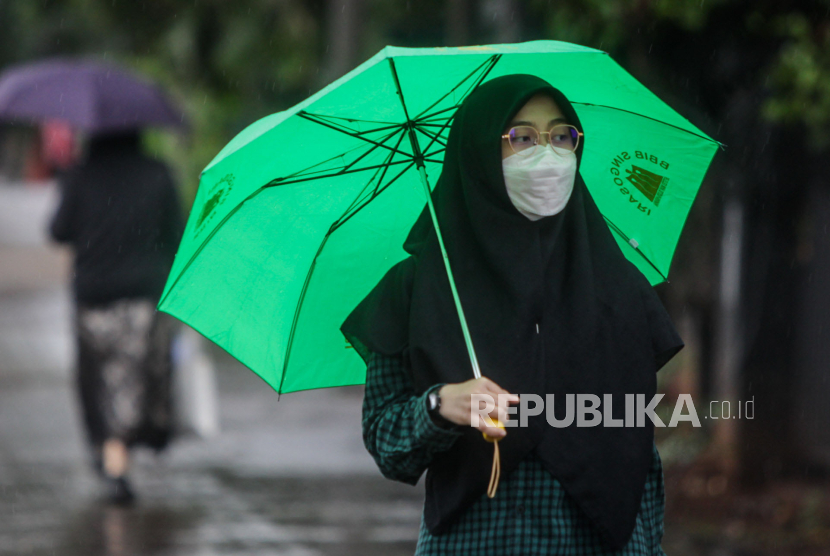 Warga memakai payung saat hujan turun, (ilustrasi). BMKG memperingatkan perubahan cuaca akibat pancaroba bisa menyebabkan penyakit.