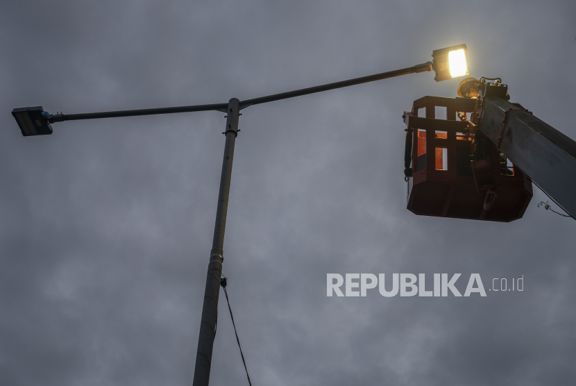 Pekerja mengetes bola lampu Penerangan Jalan Umum (PJU) di salah satu ruas jalan. 