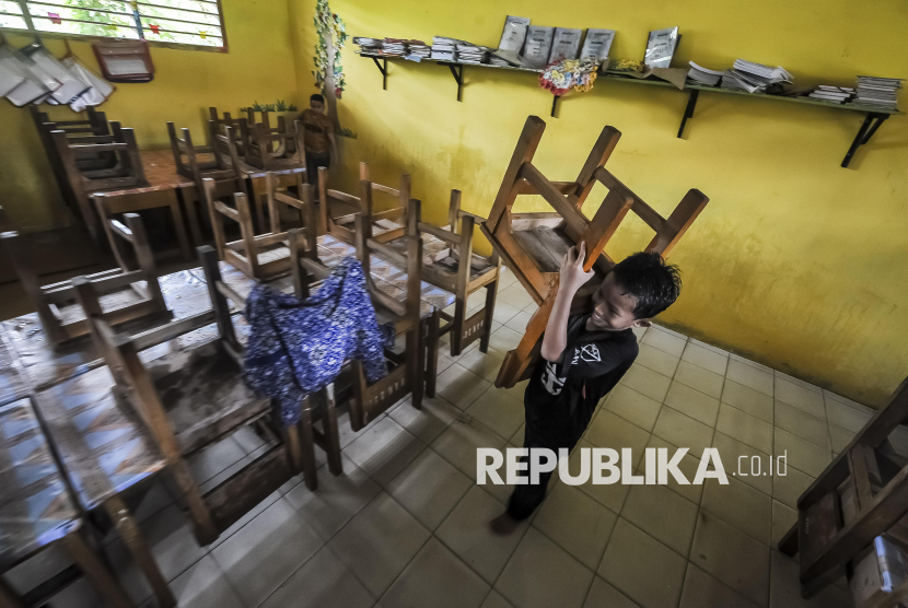 Murid memindahkan kursi saat pembersihan ruang kelas SDN 98 Kota Jambi yang terendam banjir luapan Sungai Kenali Asam di Suka Karya, Jambi, Jumat (21/2/2025). Aktivitas belajar mengajar 386 murid di sekolah yang telah mengalami banjir keempat dalam tahun ini tersebut terpaksa diliburkan. 