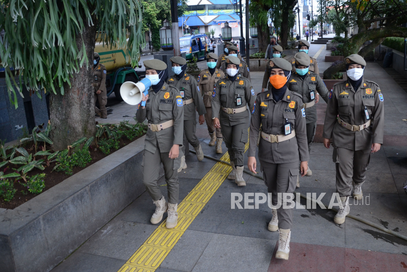 Sejumlah petugas Satpol PP Kota Bandung, berkeliling di kawasan Alun-alun, Selasa (9/2). Mereka mengingatkan pengunjung agar tidak lupa menerapkan protokol kesehatan.