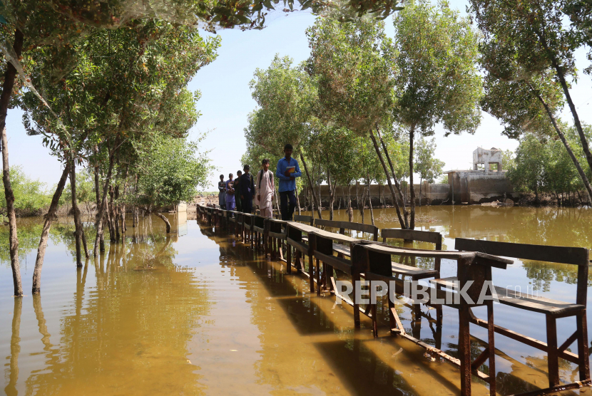  Polisi Muslim New York Kirimkan Bantuan untuk Korban Banjir Pakistan. Foto:  Siswa menggunakan bangku sekolah untuk menyeberangi banjir di sekolah yang terendam air, di distrik Mirpur Khas, provinsi Sindh, Pakistan, 10 Oktober 2022. Menurut otoritas manajemen bencana, sekitar 160 jembatan dan 5.000 km (3.200 mil) jalan hancur atau rusak, 3,5 juta hektar tanaman terpengaruh, dan sekitar 800.000 ternak hilang. Lebih dari 33 juta orang terkena dampak banjir, kata Menteri Perubahan Iklim negara itu Sherry Rehman.