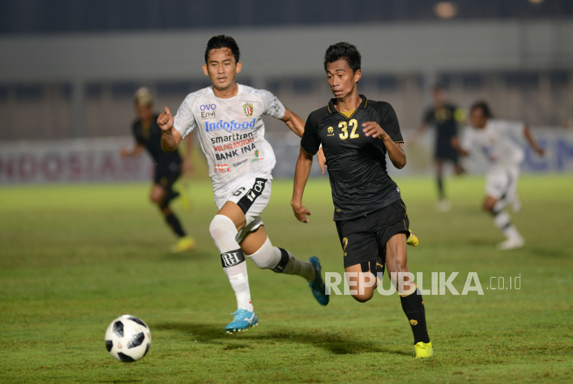 Pesepak bola Tim Nasional (Timnas) U-23 Kahar Kalu (kanan) berebut bola dengan pesepak bola klub Bali United Komang Tri dalam pertandingan uji coba di Stadion Madya, Gelora Bung Karno (GBK), Jakarta, Minggu (7/3).