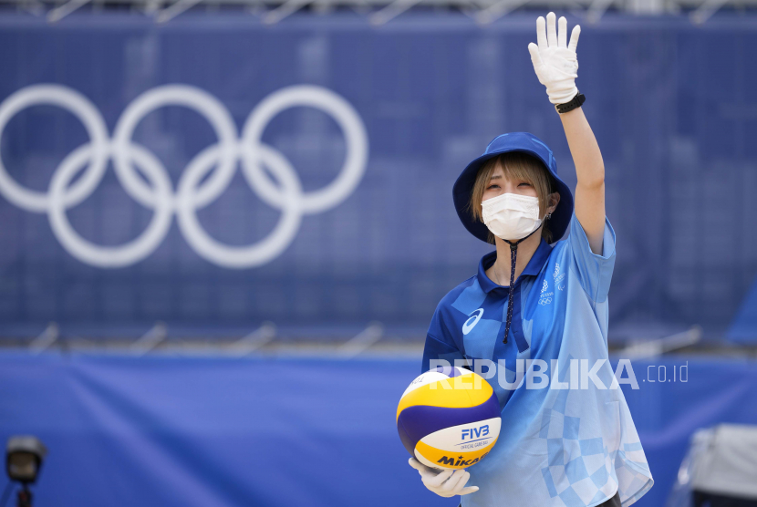 Seorang sukarelawan memegang bola sebelum pertandingan voli pantai putra di Olimpiade Musim Panas 2020, Selasa, 27 Juli 2021, di Tokyo, Jepang. Lebih dari 1,7 miliar yen atau sekitar Rp 216 T dihabiskan untuk seragam Olimpiade.