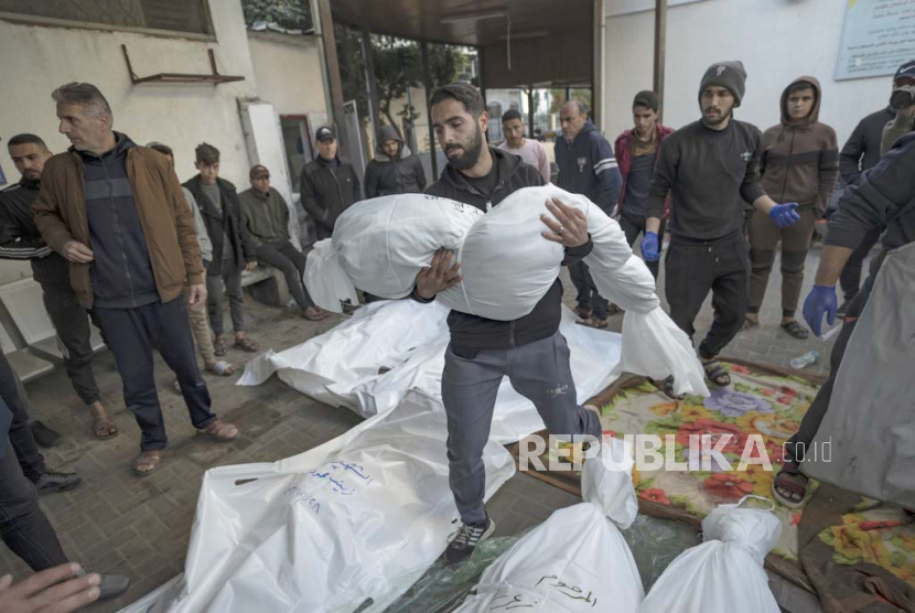 Seorang pria Palestina membawa jenazah kerabatnya yang gugur dalam pengeboman Israel di Jalur Gaza, di luar kamar mayat di Rafah, Gaza selatan, Jumat, 29 Desember 2023.